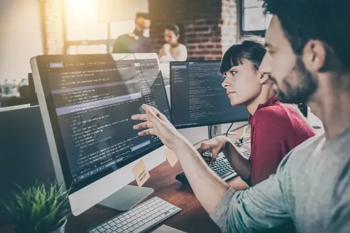 Two people, possibly software vendors, sit in front of the computer screen and see how easily VeriFactu API by fiskaly adapts to management software: ERP, POS, PMS