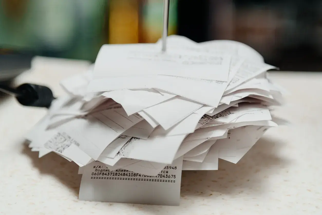 Ein Stapel Papier-Kassenbons auf einem Bonspieß an einer Ladentheke