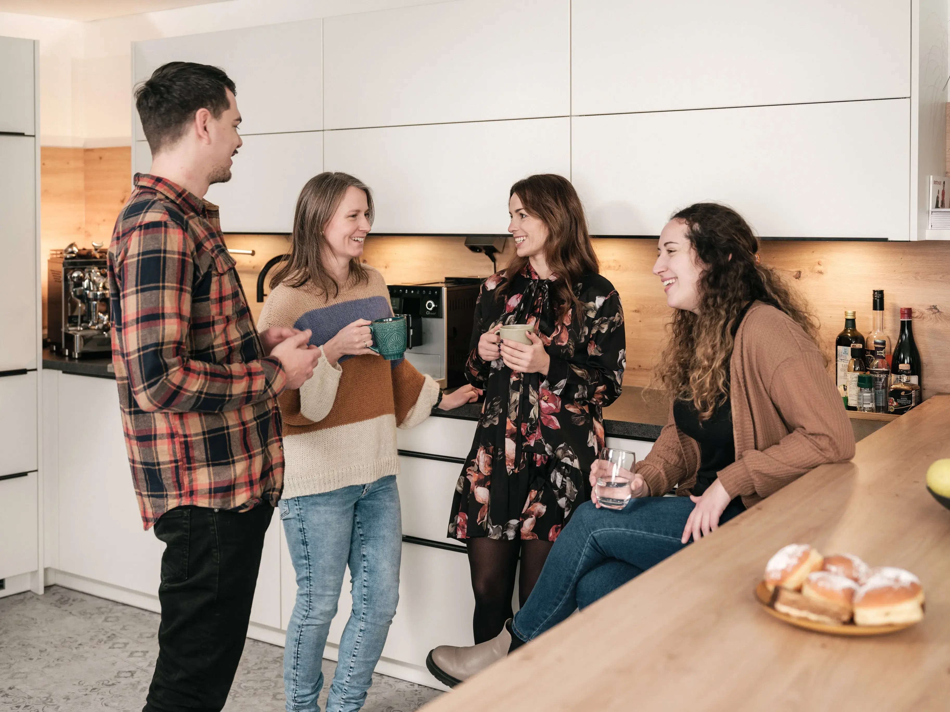 Empleados de fiskaly charlan en la cocina de la oficina de Viena con tazas de café sobre la cultura de fiskaly, la fiscalización y los e-recibos