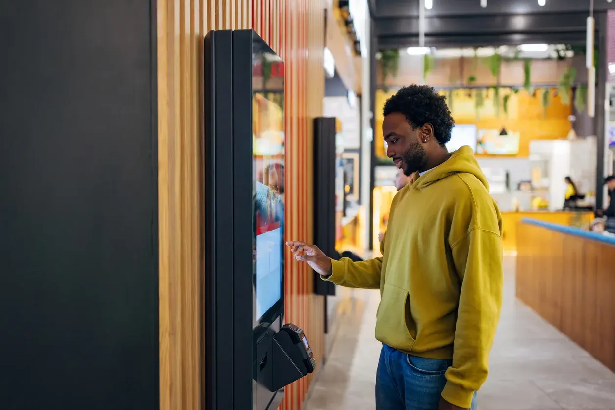 Man ordering at a self-service kiosk terminal in a restaurant