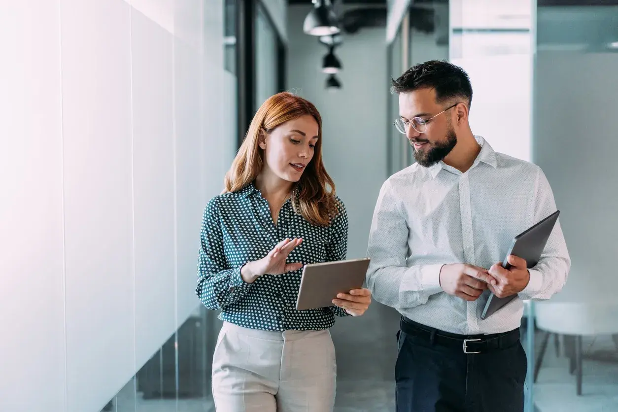 Two colleagues walking through a modern office reviewing a tablet together — fiscalization for ERP and omnichannel platforms in Sweden