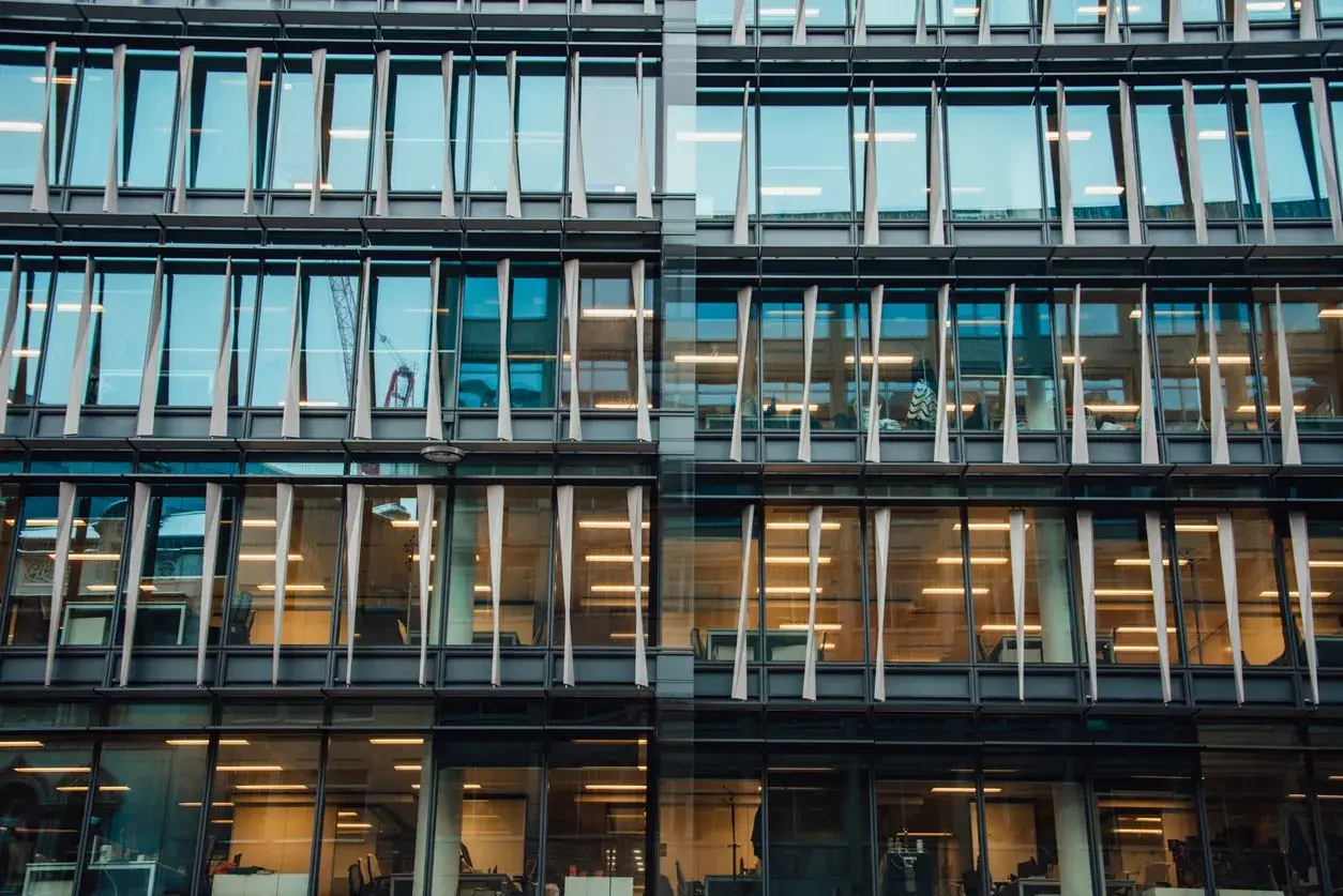 Glass facade of a modern office building with lit offices — expanding your POS platform into Sweden as a pan-European vendor