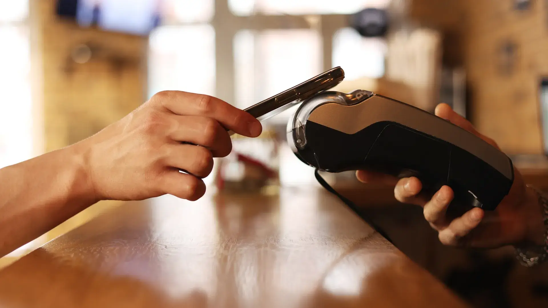 a customer puts their smartphone on a handheld device for contactless payment and automated digital receipt delivery