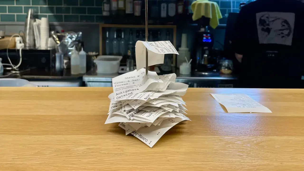 A pile of paper receipts, lying on a wooden counter