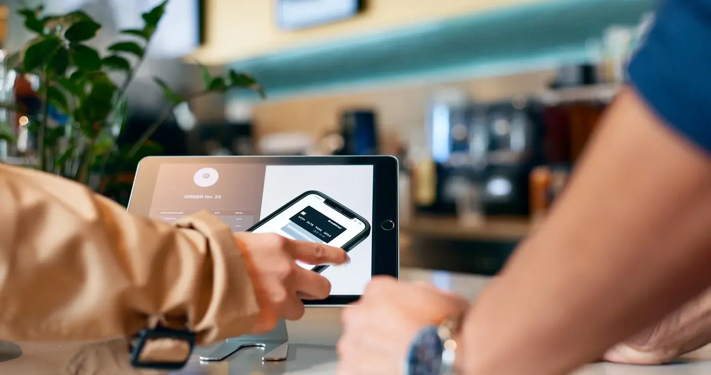 Customer paying by smartphone at a tablet POS on a café counter