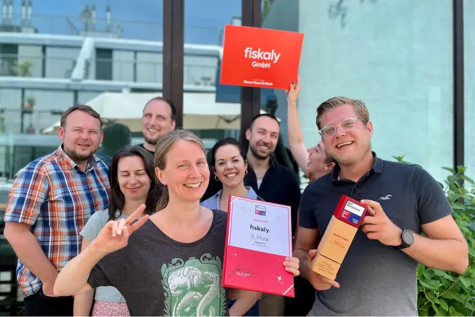 happy fiskaly employees and CEO Johannes Ferner with certifications Best Workplaces 2023 and Great Place to Work 2024 2025