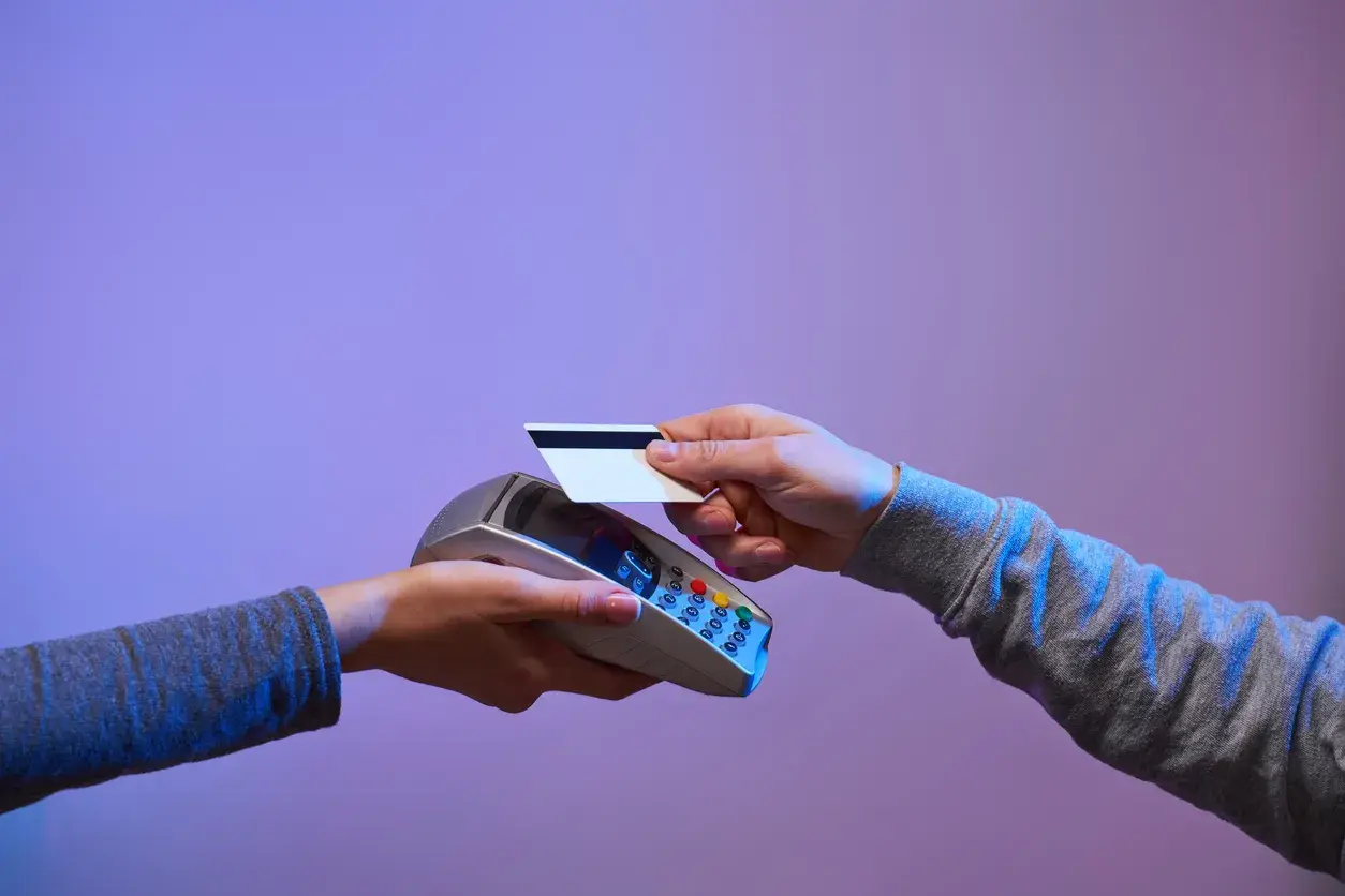 A customer taps a payment card on a handheld card terminal held by a cashier