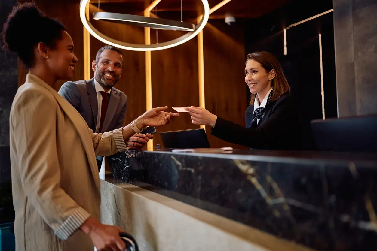 Business travelers handing a card to the receptionist at a hotel front desk