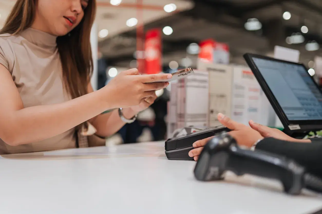 Customer tapping a contactless card at a modern POS checkout terminal.