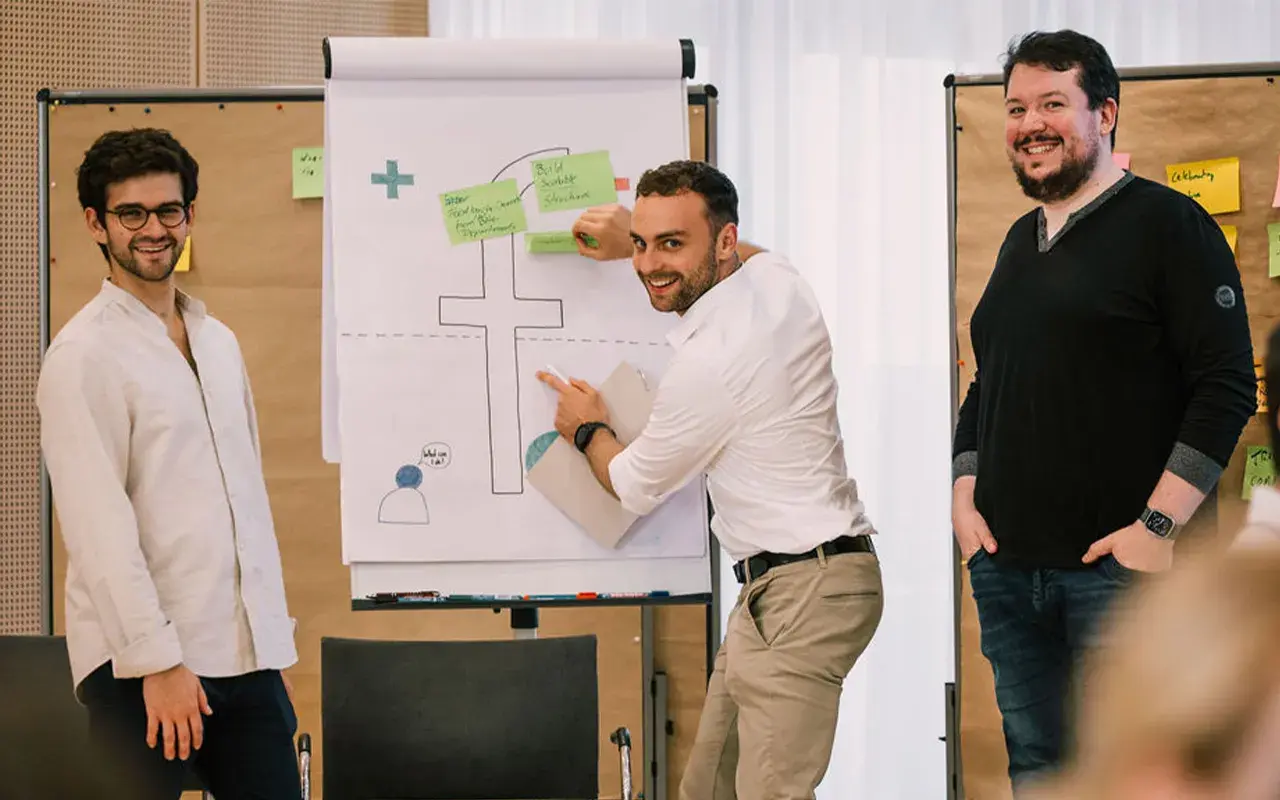 drei fiskaly Team Members vor einem Whiteboard bei einem interaktiven Workshop