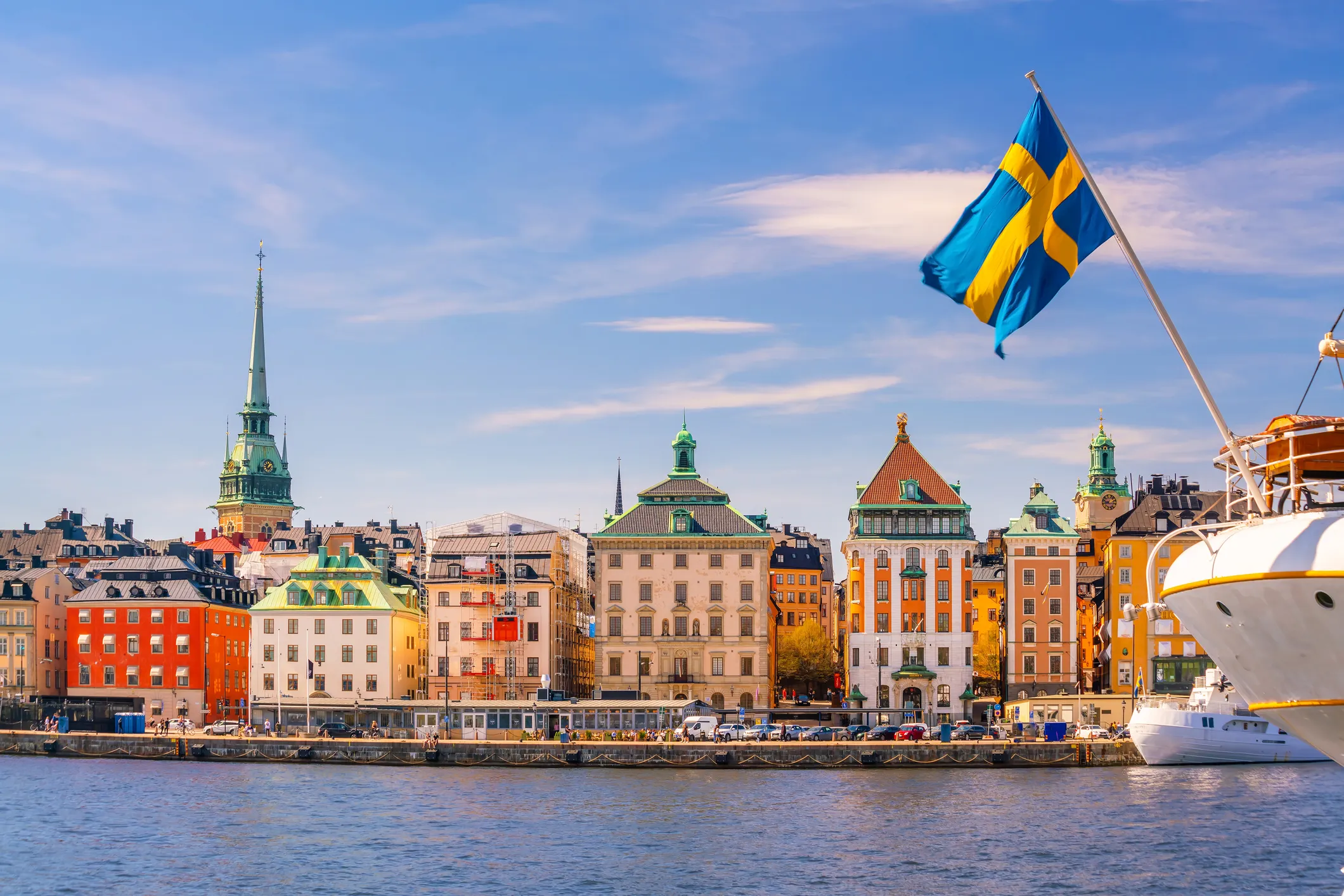 ship with a Swedish flag in front of colourful houses in Stockholm